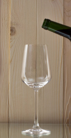 red wine being poured into a glass bottle of red wine with a brilliant glass oon a glass standの写真素材