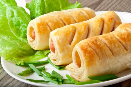 sausage in the dough on a plate with greensの写真素材