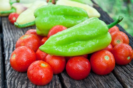 Assortment of peppers and tomato on a rustic wooden tableの写真素材
