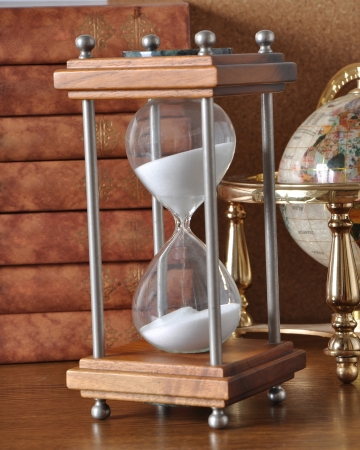 Hourglasses and book on a wooden table