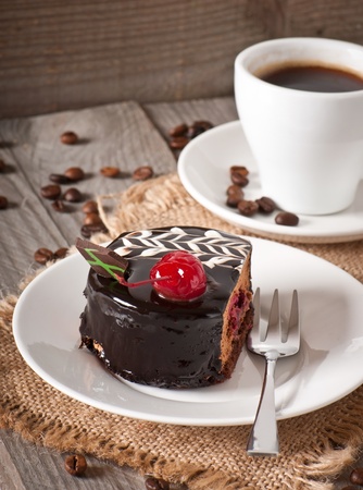 Sweet dessert fruitcake with a cherry and a cup of coffeeの写真素材