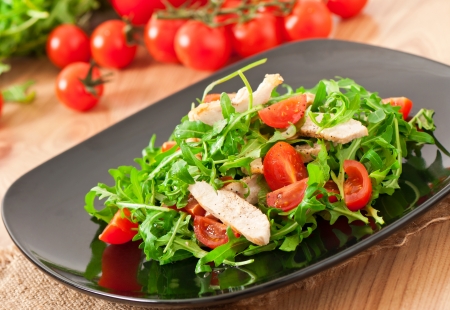 grilled fillet of chicken and a salad of arugula and tomatoの写真素材