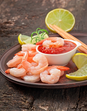tails of shrimps with fresh lemon and rosemary in plate on wooden old backgroundの写真素材