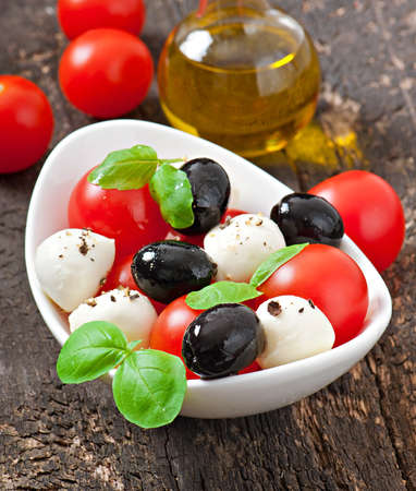 Fresh salad with cherry tomatoes, basil, mozzarella and black olives の写真素材