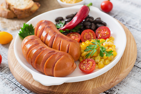 Sausages on the grill with vegetables on a platter.の写真素材