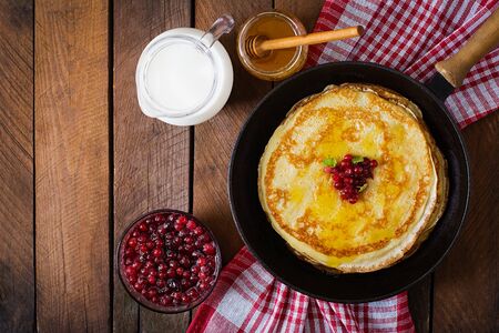 Golden pancakes with cranberry jam and honey in a rustic style. Top viewの写真素材