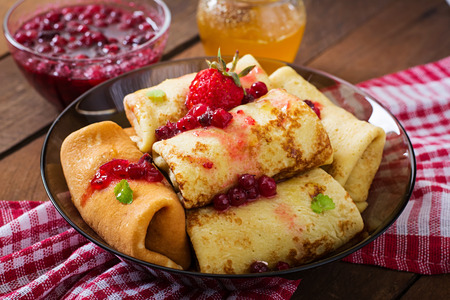 Golden pancakes with cranberry jam and honey in a rustic style.の写真素材