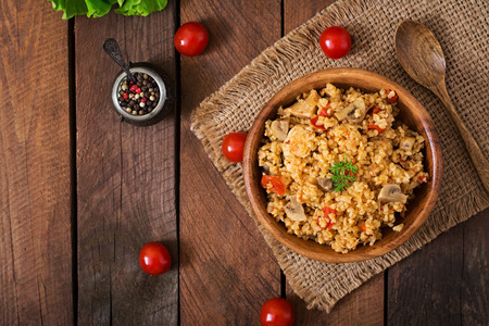 Bulgur with chicken, mushrooms and tomatoes in a wooden bowl. Top viewの写真素材