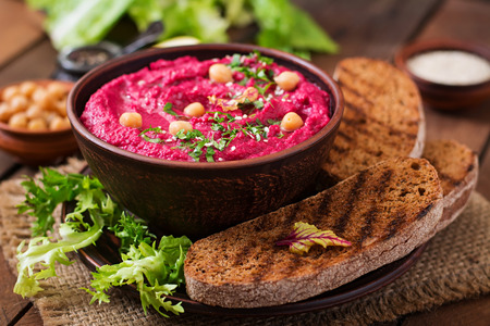 Roasted Beet Hummus with toast in a ceramic bowl on a wooden backgroundの写真素材