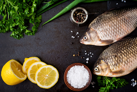 Two fresh raw crucian on a wooden background with herbs. Top viewの写真素材