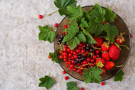 Plate with fresh berries (strawberries and currants) on grey background. Top viewの写真素材