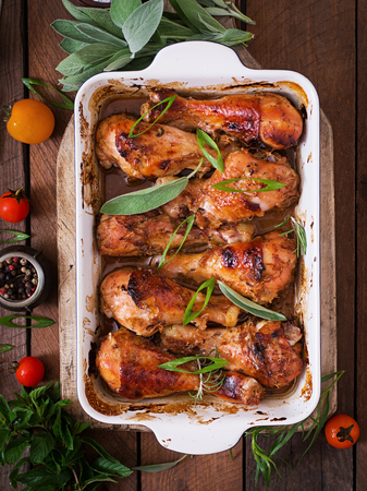 Appetizing oven baked golden chicken drumsticks in a baking dish on a wooden table. Top viewの写真素材