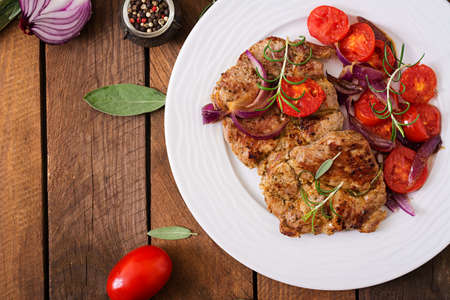 Juicy pork steak with rosemary and tomatoes on a white plate. Top viewの写真素材