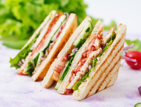 Club sandwich with chicken breast, bacon, tomato, cucumber and herbsの写真素材