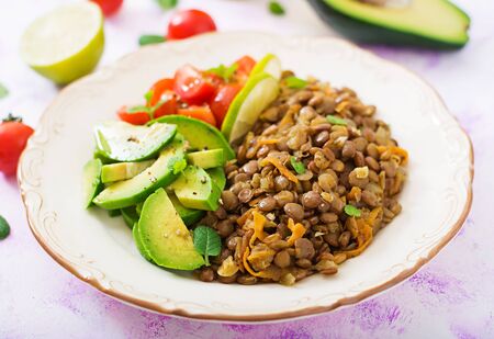Diet menu. Healthy lifestyle. Lentils porridge and fresh vegetables - tomatoes and avocado on plate.の写真素材