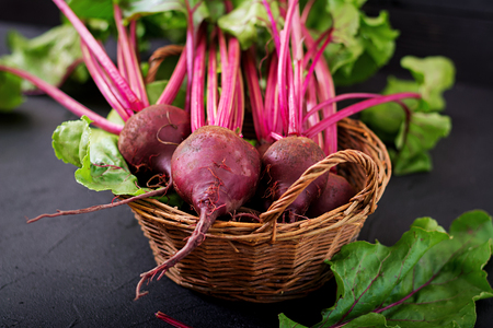 Young beetroot with a tops in a basket on a dark background.の写真素材