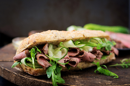 Sandwich of whole wheat bread with roast beef, cucumber and arugulaの写真素材