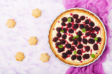 Tart with blackberry and cheesecake cream decorated with mint leaves. Top view. Flat layの写真素材