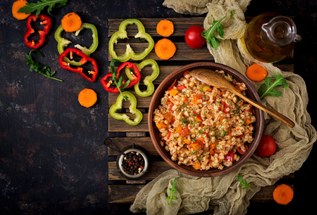 Vegetarian crumbly pearl barley porridge with vegetables  in a dark background. Flat lay. Top viewの写真素材