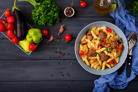 Penne pasta with meatballs in tomato sauce and vegetables in bowlの写真素材
