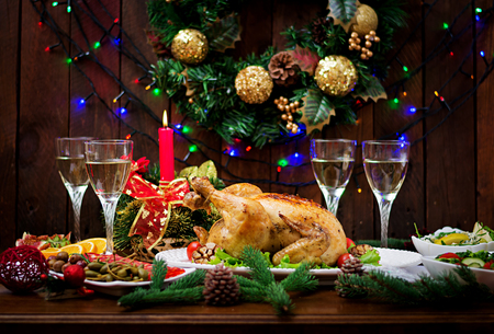 Baked turkey or chicken. The Christmas table is served with a turkey, decorated with bright tinsel and candles. Fried chicken, table. Christmas dinner.の写真素材