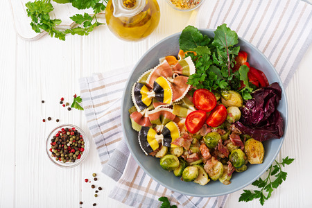 Bowl with Farfalle pasta, Brussels sprouts with bacon and fresh vegetable salad. Flat lay. Top viewの写真素材