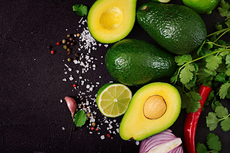 Guacamole sauce ingredients - avocado,  onion, pepper chili, garlic, cilantro, lime on black...