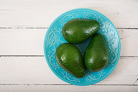 Three ripe avocados on a wooden table. Healthy food concept. Top view