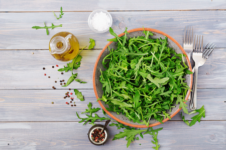 Fresh leaves of arugula in a bowl on a light wooden background. Flat lay. Top viewの写真素材