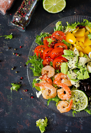 Healthy salad plate. Fresh seafood recipe. Grilled shrimps and fresh vegetable salad - avocado, tomato, black beans, red cabbage and paprika. Grilled prawns. Healthy food. Flat lay. Top viewの写真素材