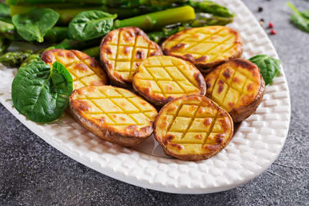 Halves of baked potatoes and asparagus. Dietary menu. Healthy food. Vegan cuisine.
