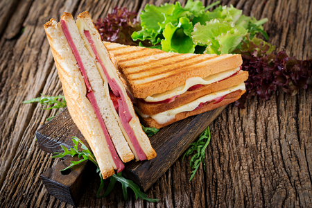 Club sandwich - panini with ham and cheese on wooden background. Picnic food.の写真素材