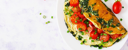 Omelette with tomatoes, spinach and green onion on white plate.  Frittata - italian omelet. Top view. Flat lay. Bannerの写真素材