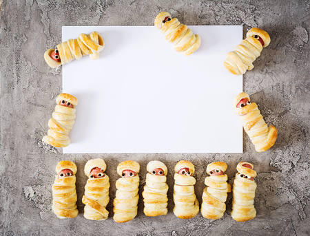 Scary sausage mummies in dough with funny eyes on table. Mockup decoration. Halloween food. Top view. Flat layの写真素材