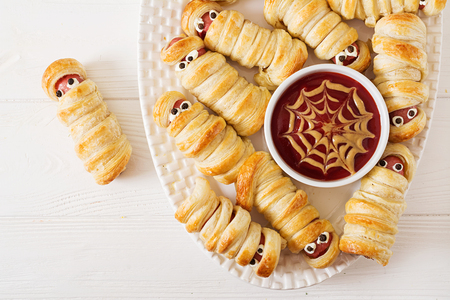 Scary sausage mummies in dough with funny eyes on table. Funny decoration. Halloween food. Top view. Flat layの写真素材