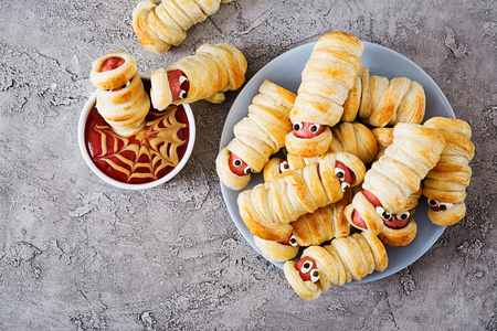 Scary sausage mummies in dough with funny eyes on table. Funny decoration. Halloween food. Top view. Flat layの写真素材