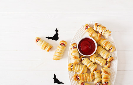 Scary sausage mummies in dough with funny eyes on table. Funny decoration. Halloween food. Top view. Flat layの写真素材