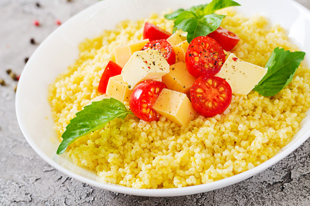 Millet porridge with cheese, butter and basil in white bowl. Tasty food. Breakfast.の写真素材