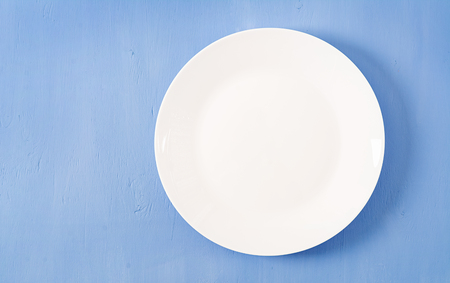 Top view of blank white dish on a blue background. Copy space. Mockupの写真素材