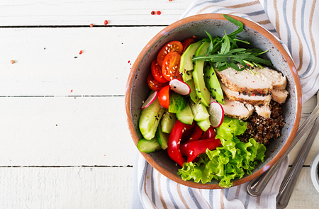 Buddha bowl dish with chicken fillet, quinoa, avocado, sweet pepper, tomato, cucumber, radish, fresh lettuce salad and sesame. Detox and healthy superfoods bowl concept. Overhead, top view, flat lay.の写真素材