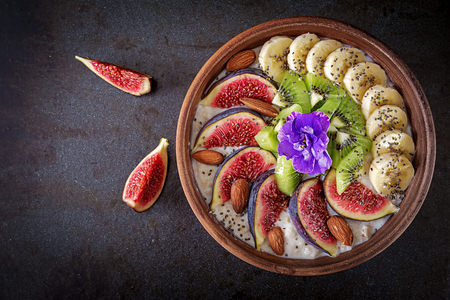 Delicious and healthy oatmeal with figs, kiwi, banana, almond and chia seeds. Black background. Healthy breakfast. Fitness food. Proper nutrition. Flat lay. Top view.の写真素材