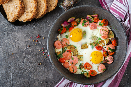 Frying pan with tasty cooked egg, sausages and vegetables on grey table. Breakfast. Top viewの写真素材