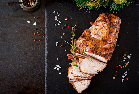Roasted sliced Christmas ham of turkey on dark rustic background. Top view. Festival food.の写真素材