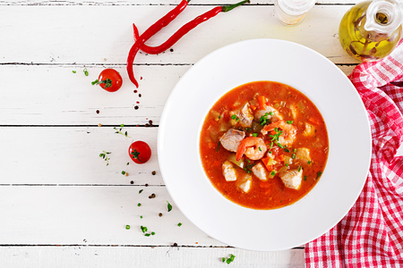 Brazilian food: Moqueca capixaba of fish and bell peppers in spicy coconut sauce  in a plate on a white wooden table. Brazilian fish stew. Top viewの写真素材