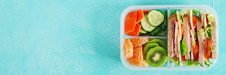 School lunch box with sandwich, vegetables, water, and fruits on table. Healthy eating habits concept. Flat lay. Banner. Top viewの写真素材