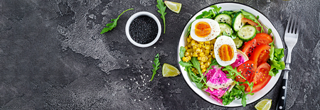 Fresh salad. Bowl with fresh raw vegetables - cucumber, tomato, watermelon radish, lettuce, arugula, corn and boiled egg. Healthy food. Vegetarian buddha bowl. Banner. Top view. Flat layの写真素材