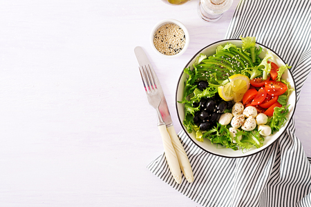 Fresh salad with avocado, tomato, olives and mozzarella  in a  bowl. Buddha bowl. Fitness food. Vegetarian meal. Top viewの写真素材