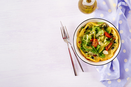 Omelet with fresh tomatoes, black olive, avocado and mozzarella cheese. Omelette salad. Breakfast. Healthy food. Top view. Flat layの写真素材