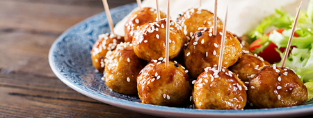 Meatballs in sweet and sour glaze on a plate with pita bread and vegetables in a Moroccan style on a wooden table. Tapas.  Banner. Trend food.の写真素材