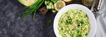 Healthy salad. Spring vegan salad with cabbage, cucumber, green onion and parsley on dark table. Banner. Top viewの写真素材